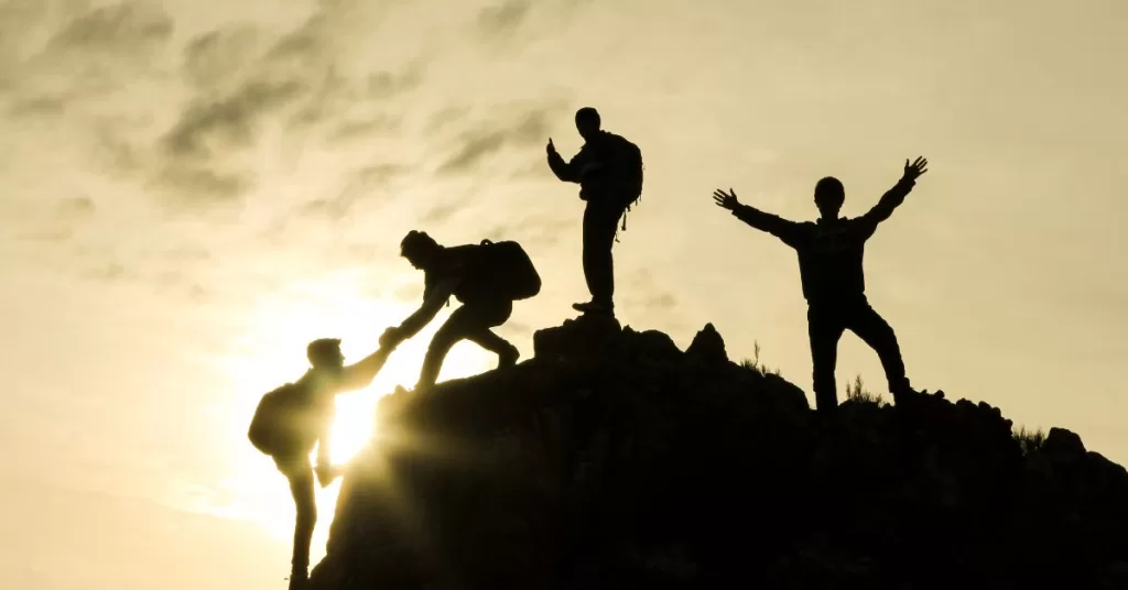 Group of 4 reaching mountain summit