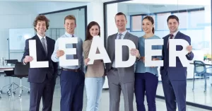 Group of people holding letters spelling "leader"